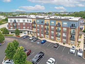 A parking lot in front of a multi-story apartment building.